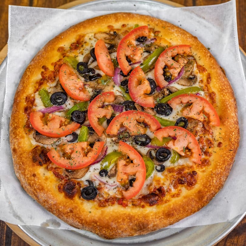 La Pizzeria's whole pizza with tomatoes, olives, green peppers, mushrooms, and red onions.